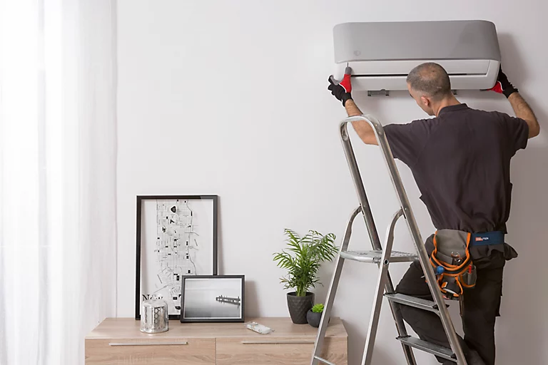Técnico instalando una unidad split en la pared de un salón